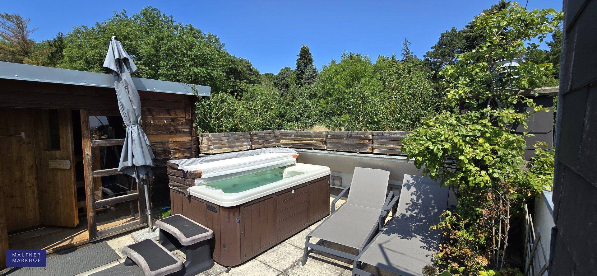 Entspannungsbereich im Freien mit Whirlpool, Saunahaus und Liegestühlen unter blauem Himmel.