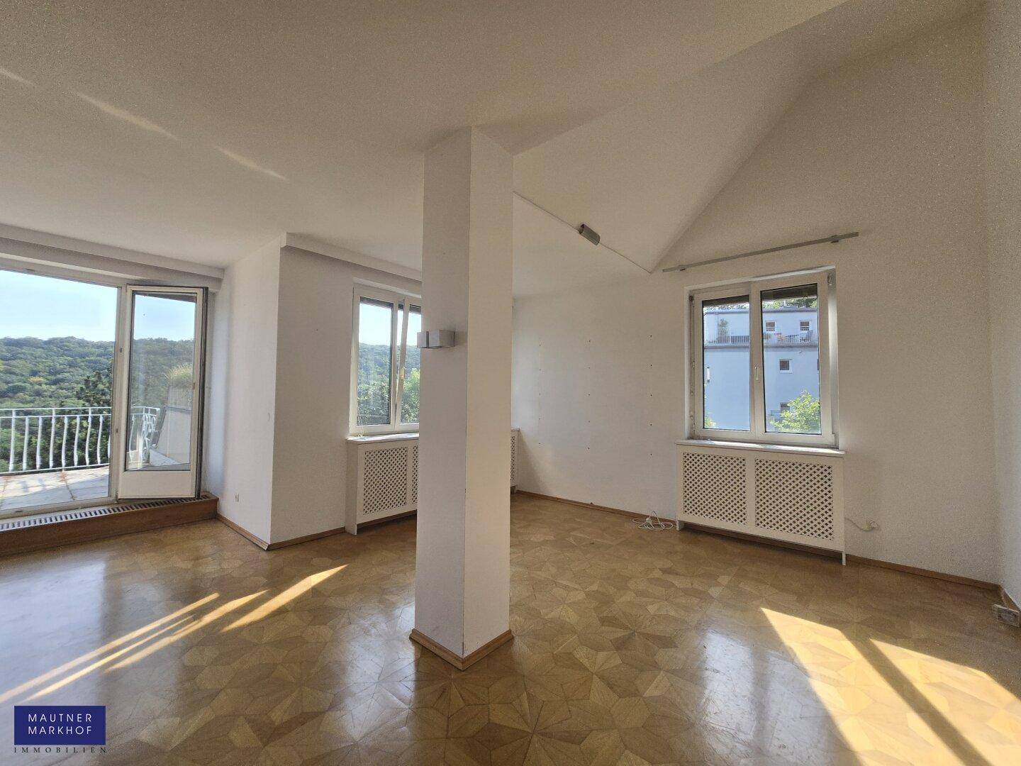 Lichtdurchflutetes Wohnzimmer mit Parkettboden, Balkonzugang und weitem Blick ins Grüne.