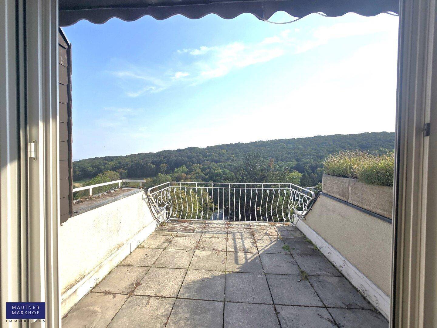 Geräumige Terrasse mit schmiedeeisernem Geländer und weitem Blick auf die umliegende Natur.