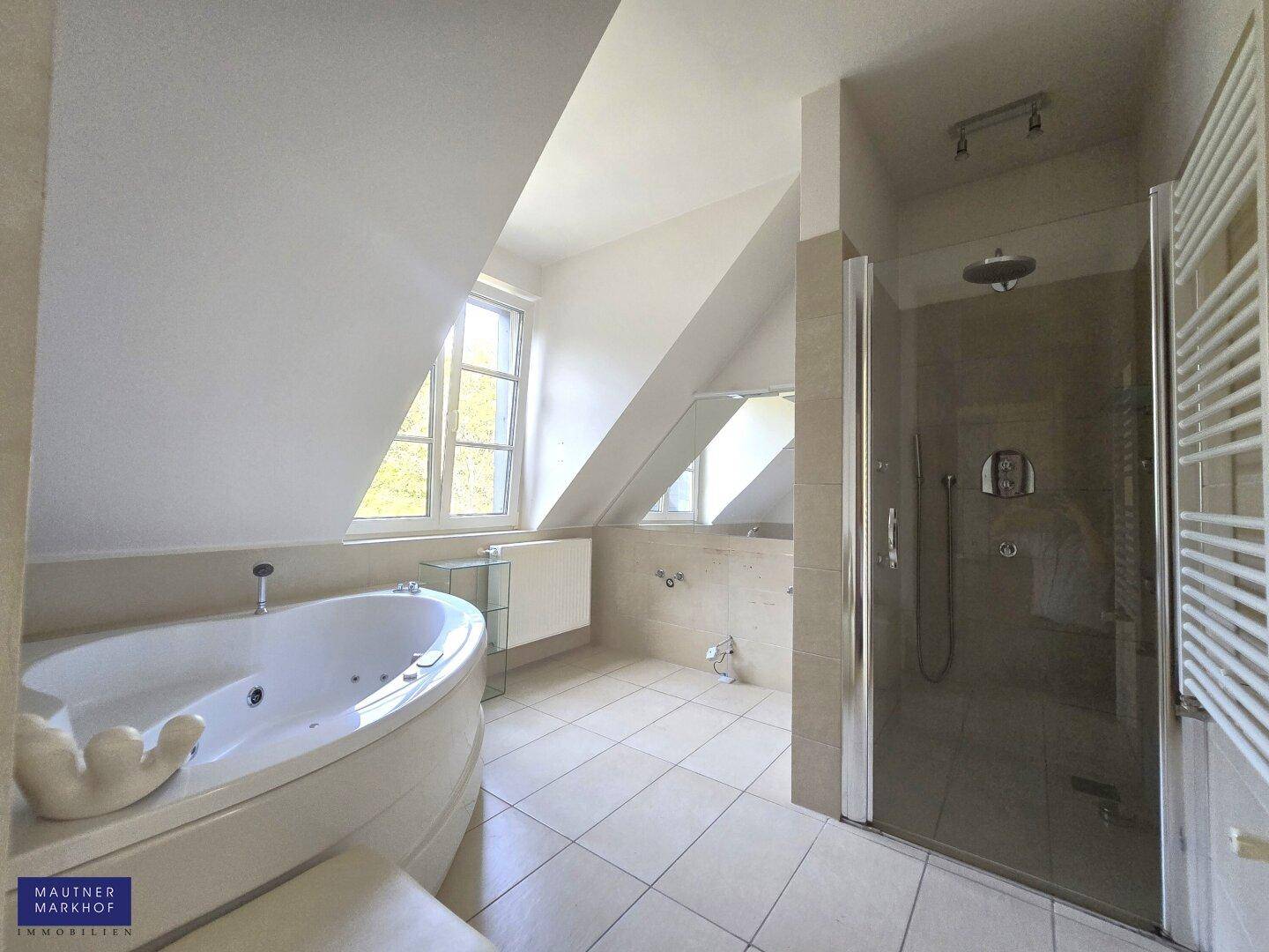 Modernes Badezimmer mit Eckbadewanne, Regendusche und Dachschrägen für ein Spa-Erlebnis.