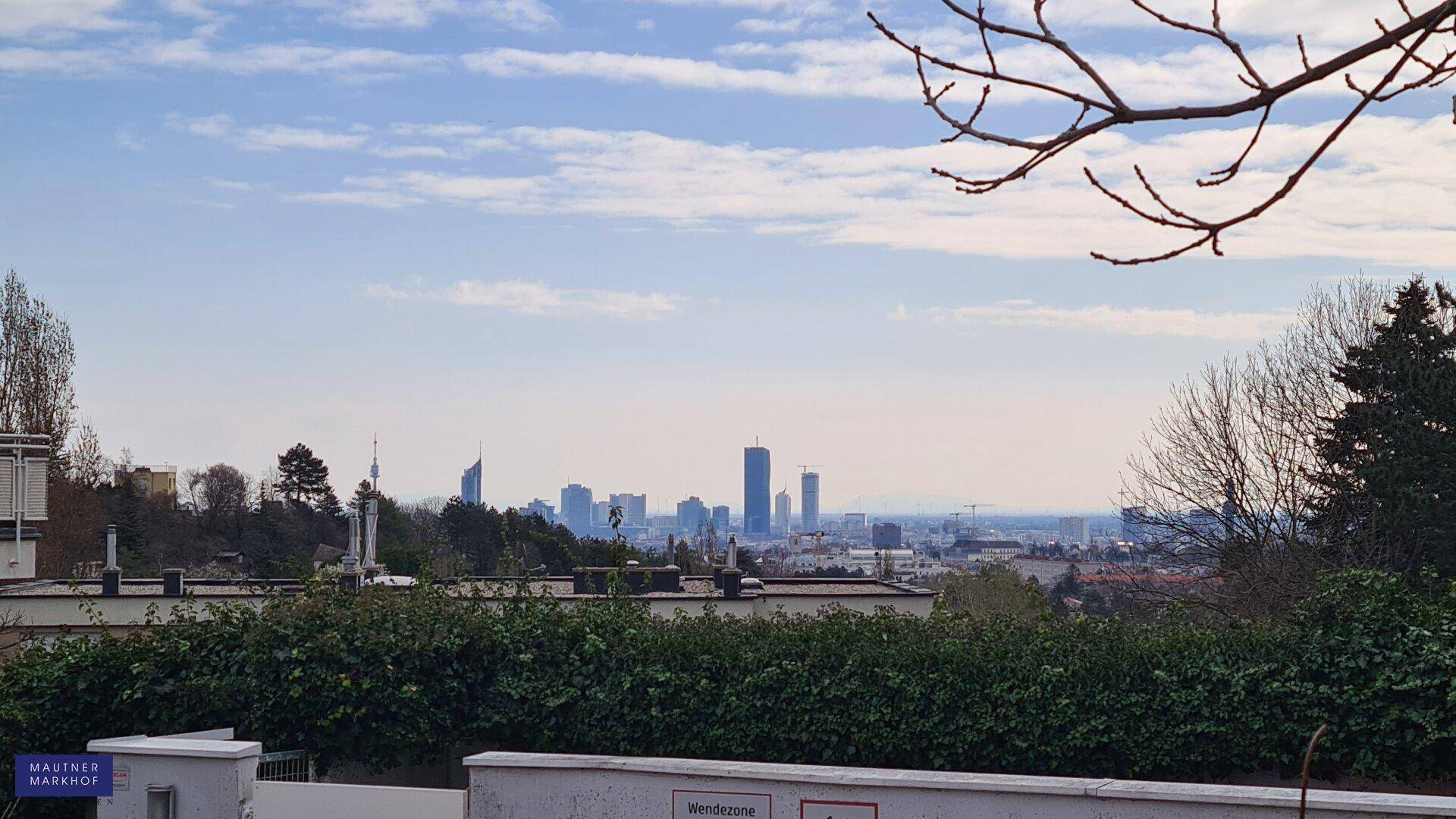 Weitblick auf die Stadt mit markanten Hochhäusern und umliegender grüner Landschaft.