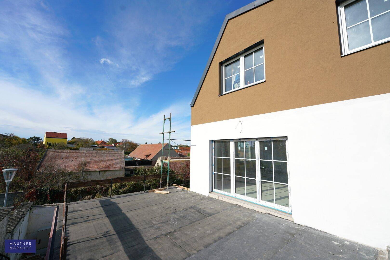 Große Dachterrasse im Bau mit Blick auf die Umgebung und die moderne Fassade des Neubaus.