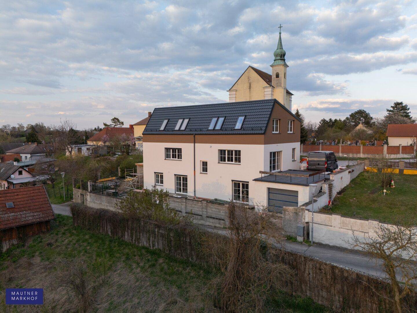 Luftaufnahme des Neubaus mit Blick auf die Seitenfassade und die umliegende Bebauung.