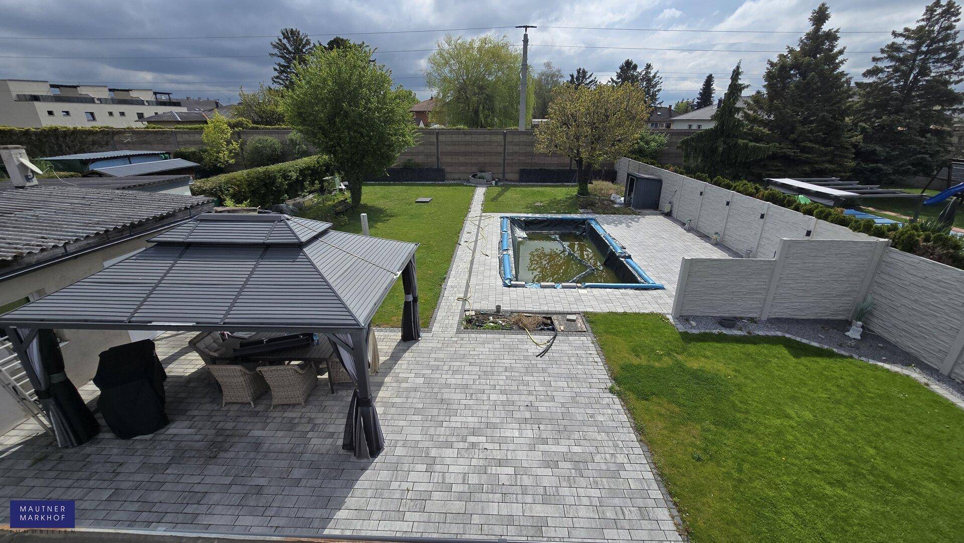 Weitläufiger Gartenbereich mit Pool, überdachtem Sitzbereich und gepflegter Rasenfläche.