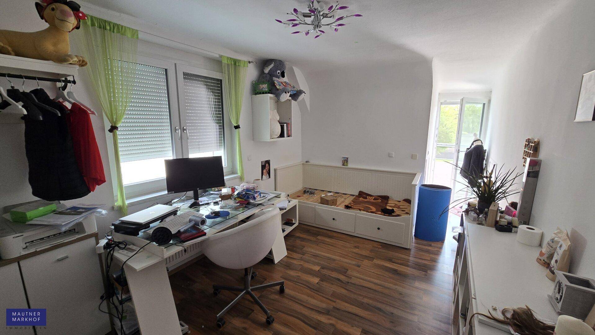 Helles Arbeitszimmer mit Schreibtisch, Fenster und Holzboden.