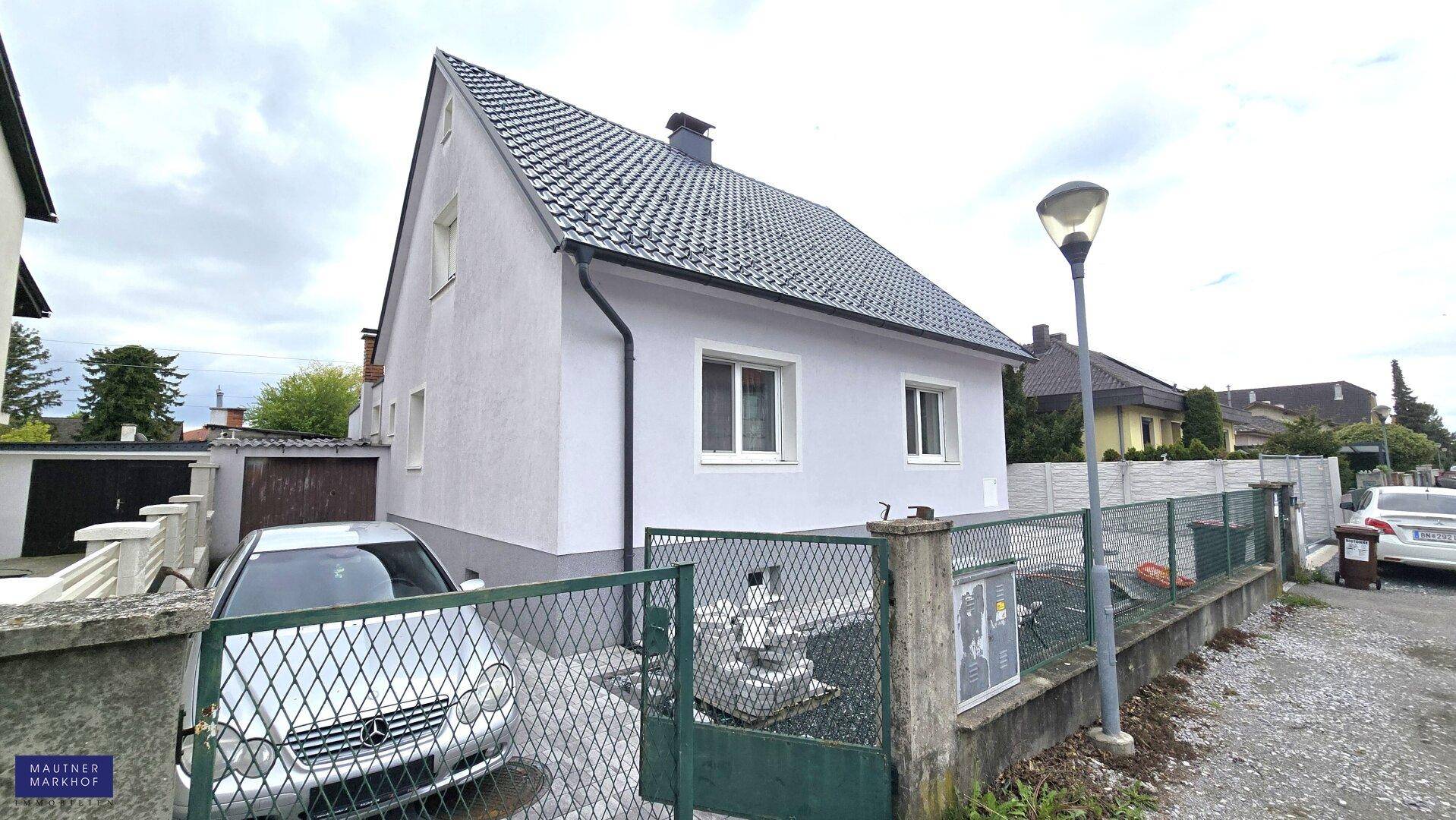 Ansicht des Einfamilienhauses von der Straße mit Vorgarten und Zaun.