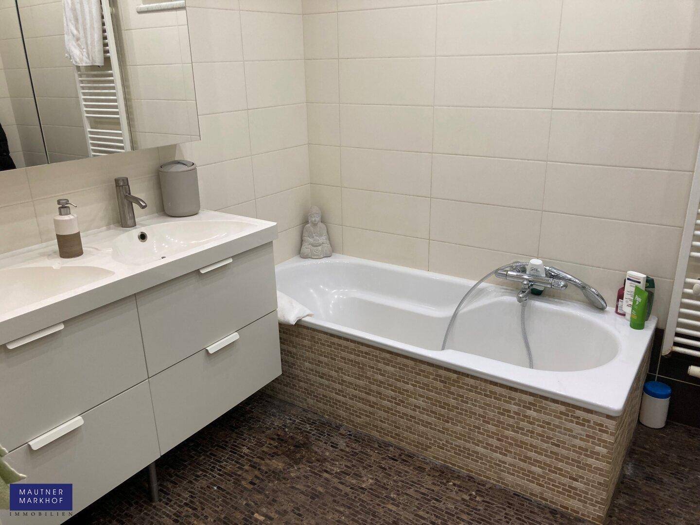 Modernes Badezimmer mit Badewanne, Einzelwaschbecken und beheiztem Handtuchhalter.
