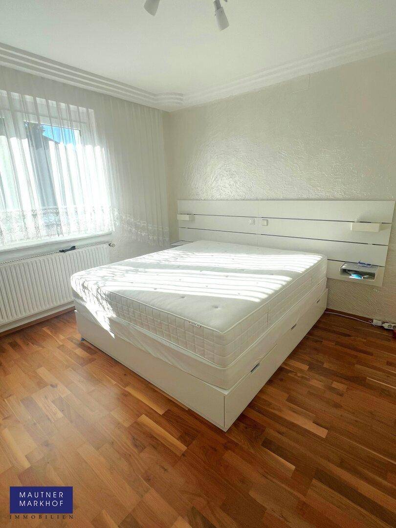 Helles Schlafzimmer mit Holzboden, großem Doppelbett und weißem Kleiderschrank.