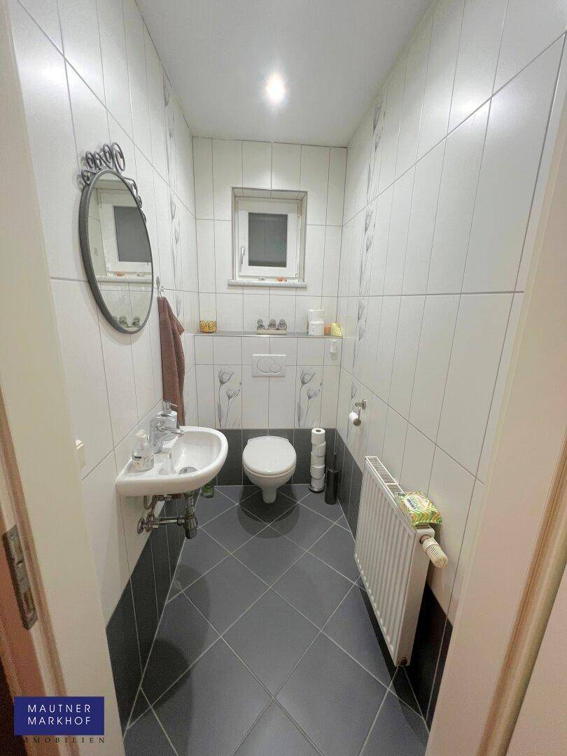 Kleines Gäste-WC mit Fenster, Wand-WC und modernem Waschbecken.