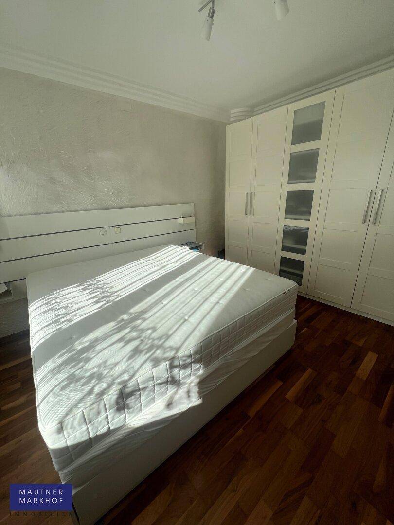 Helles Schlafzimmer mit Holzboden, großem Doppelbett und weißem Kleiderschrank.
