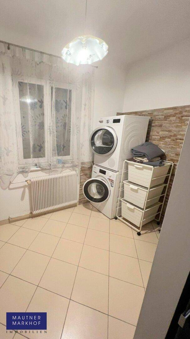 Praktischer Hauswirtschaftsraum mit Waschmaschine, Trockner und Fenster.