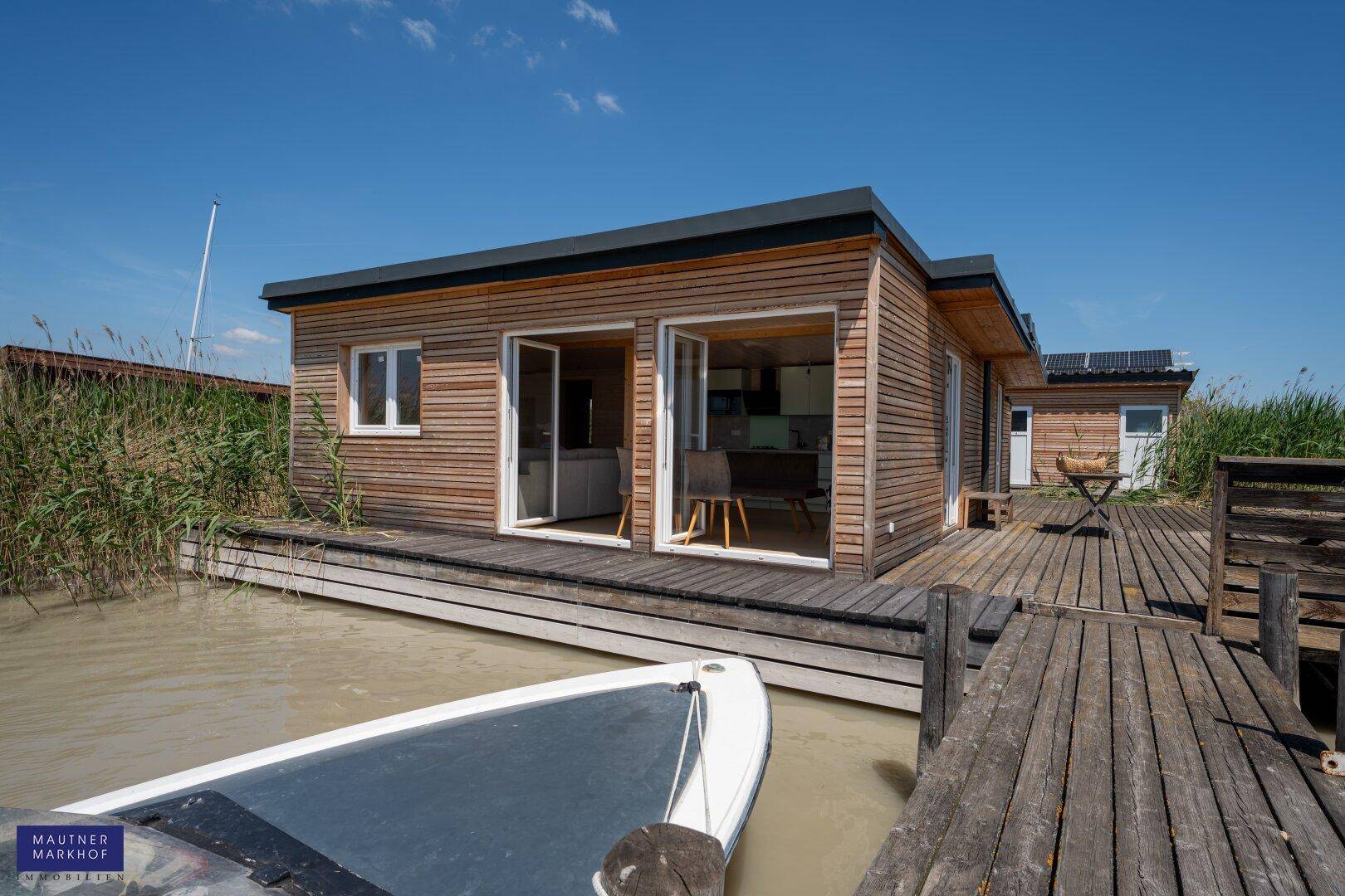 Modernes Holzhaus am Wasser mit Bootsanleger und Terrasse.