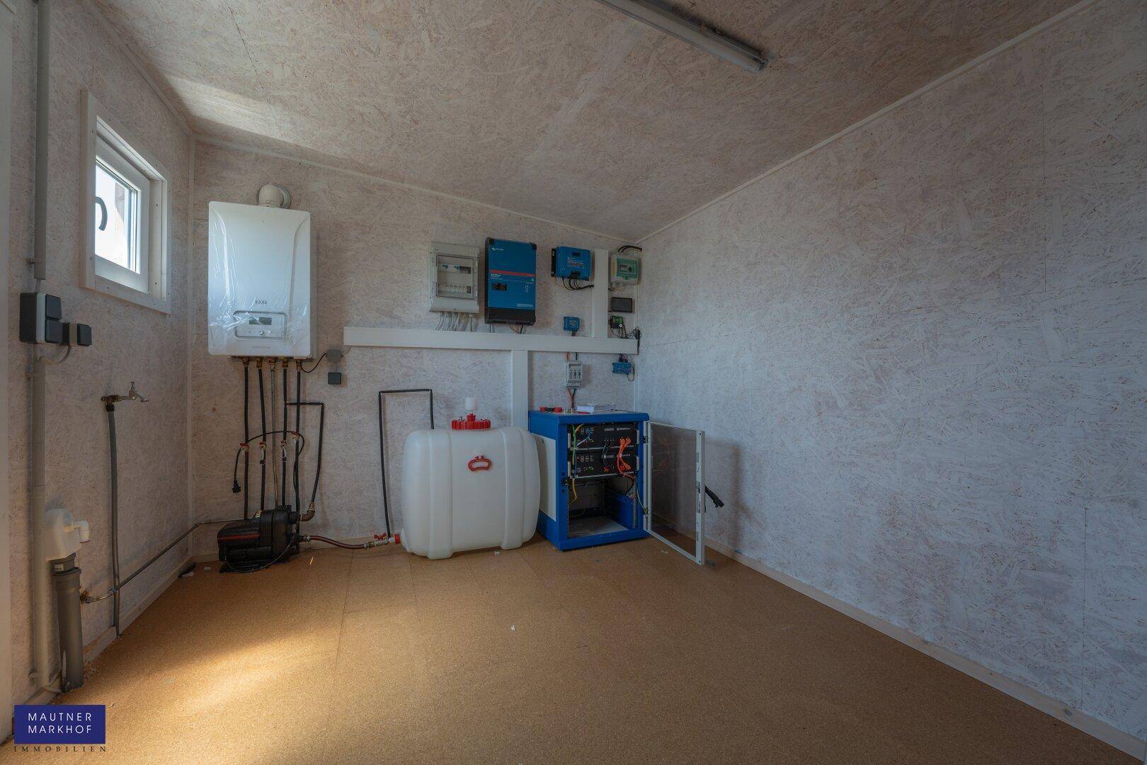 Technikraum mit Heizungsanlage, Wassertank und elektrischen Installationen.