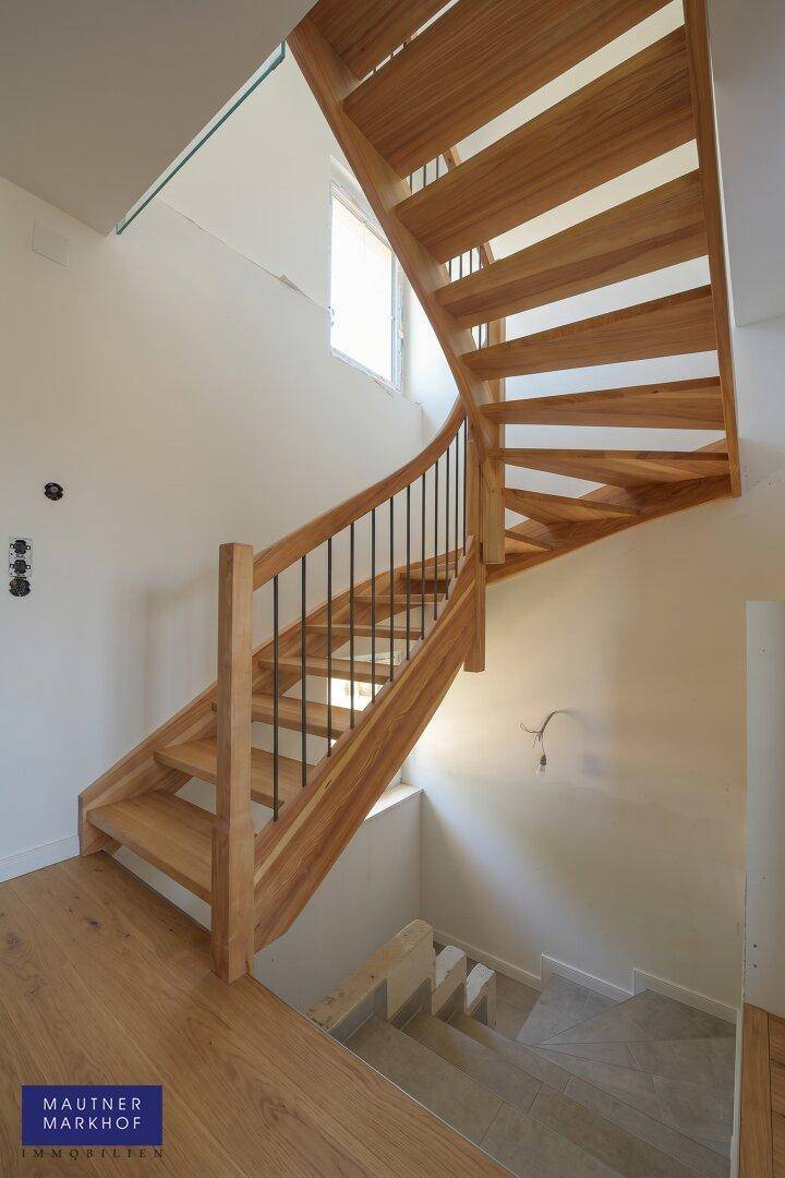 Moderne Holztreppe mit elegantem Metallgeländer, die die verschiedenen Ebenen des Hauses verbindet.