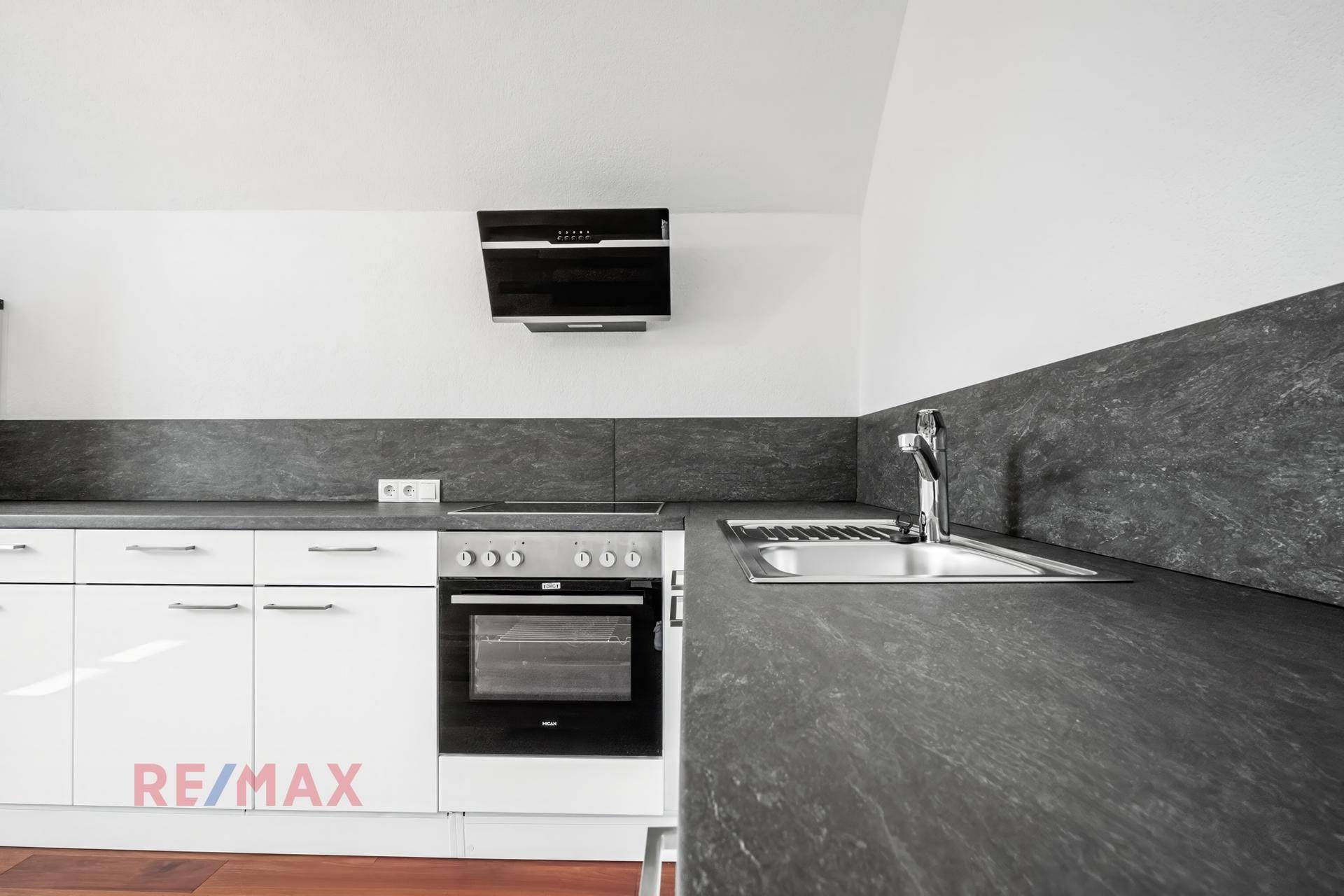 Detailansicht der modernen Küche mit integriertem Backofen, Spüle und Dunstabzugshaube.