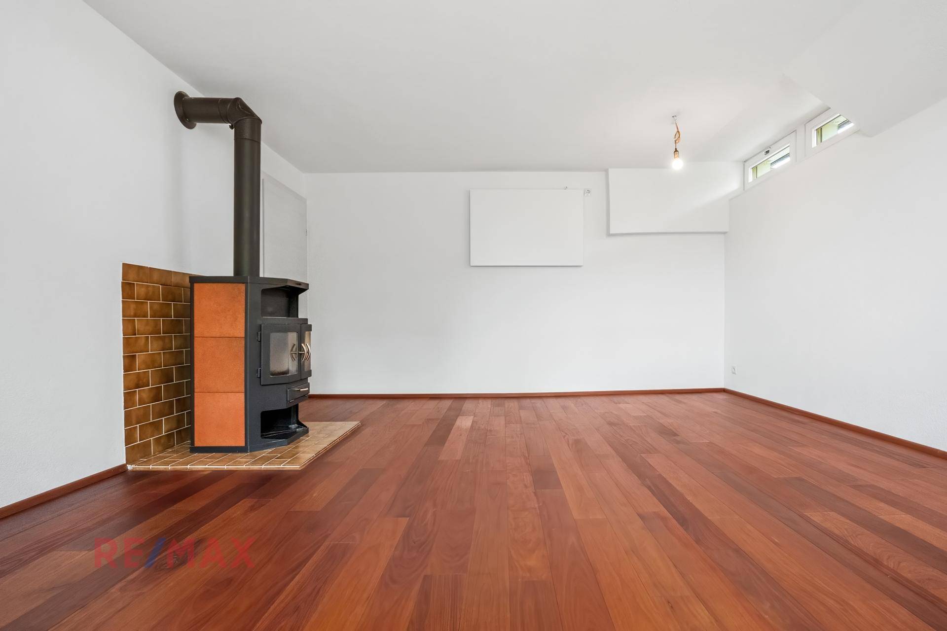 Gemütlicher Wohnbereich mit Holzboden und einem modernen Holzofen, der für Wärme sorgt.