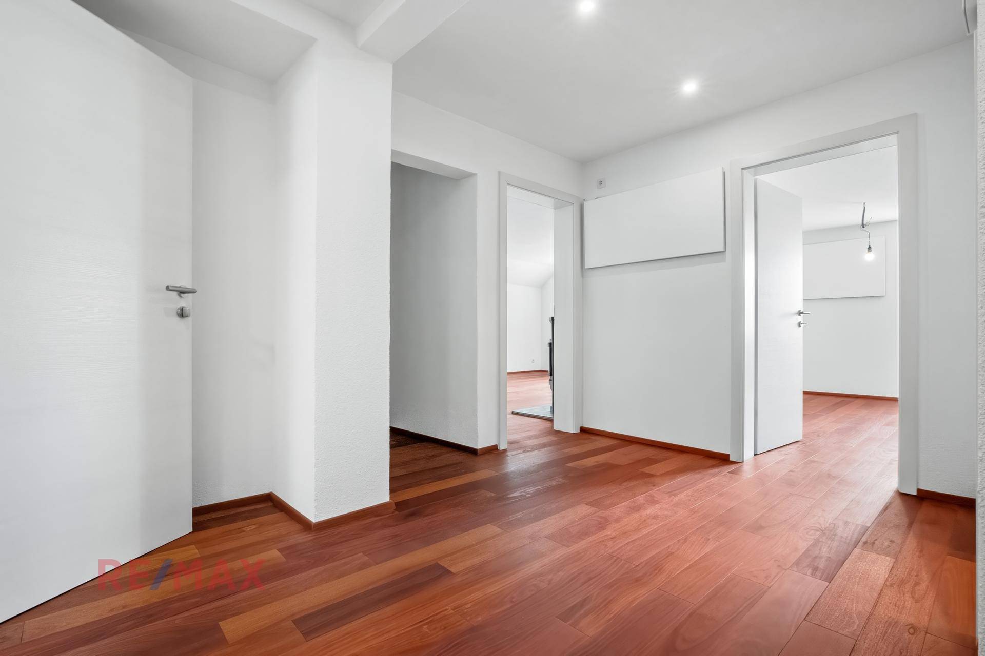 Geräumiger Flur mit Holzboden und mehreren Türen, der zu verschiedenen Zimmern führt.