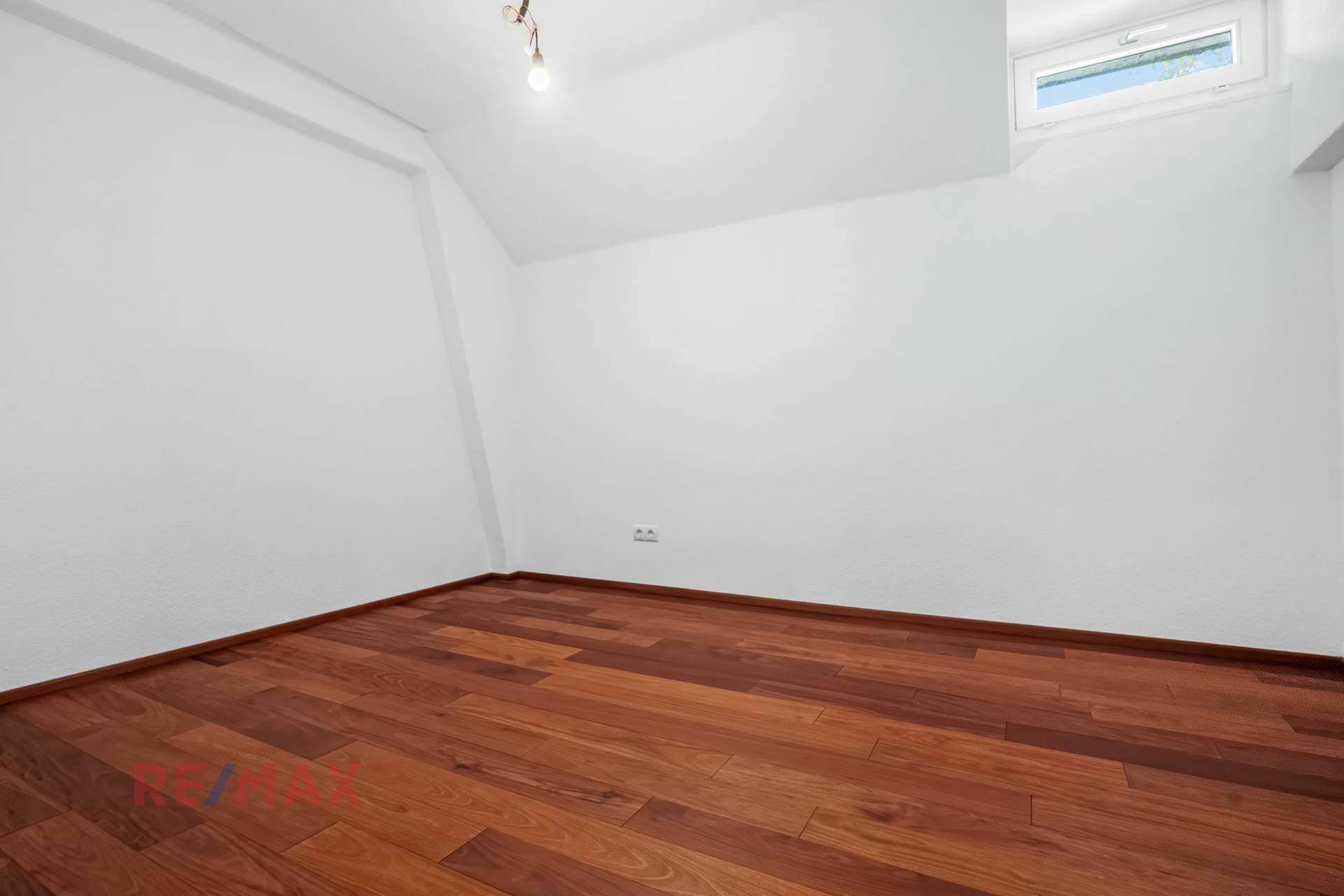 Helles Zimmer mit Holzboden und Dachschräge, ideal für ein Schlafzimmer oder Büro.