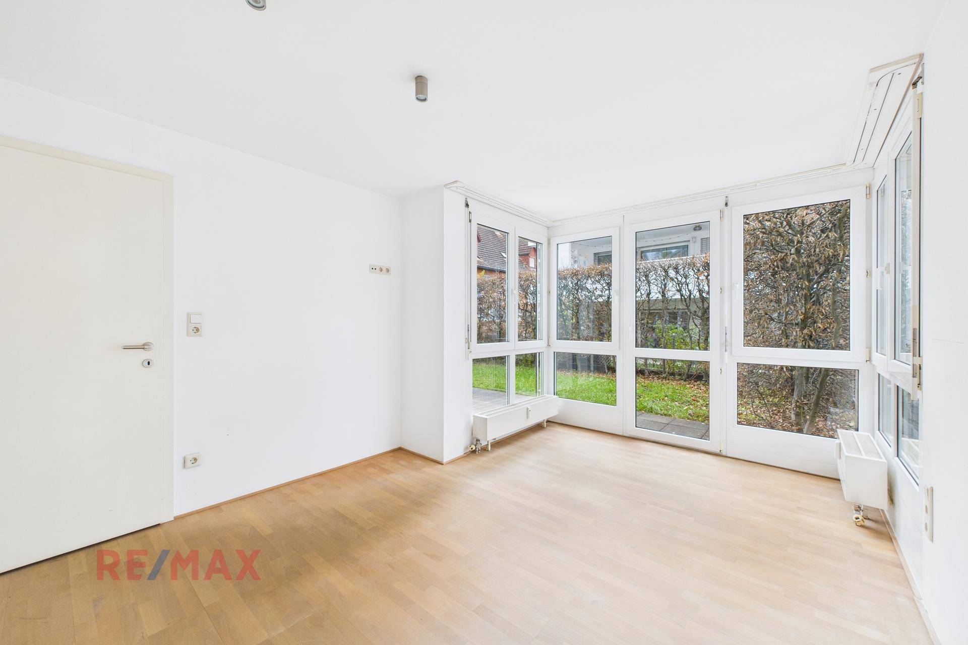 Geräumiger Raum mit großen Fenstern, die viel Licht hereinlassen und Zugang zum Außenbereich bieten.