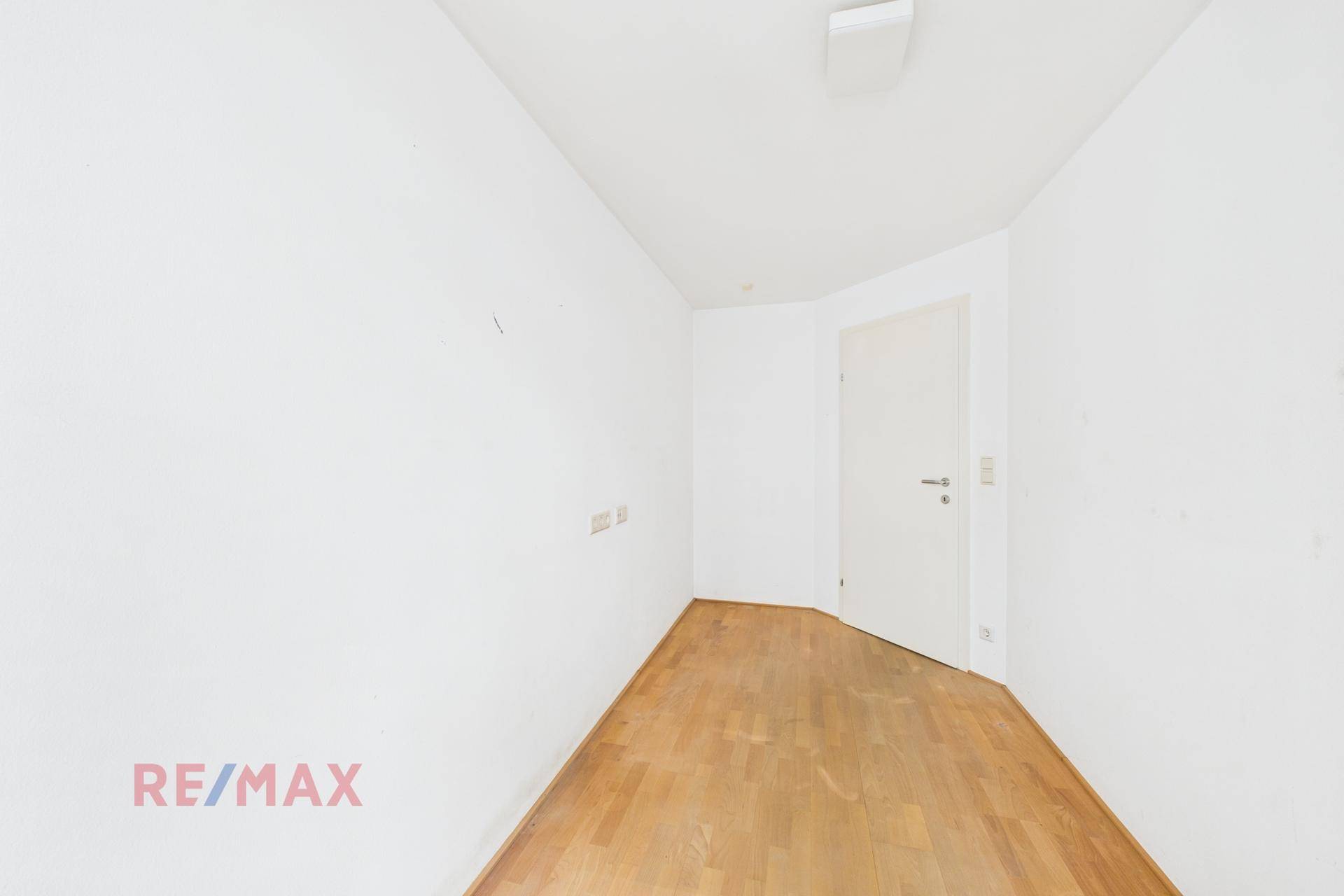 Leerer Raum mit hellem Holzboden und weiß gestrichenen Wänden, bereit zur individuellen Gestaltung.
