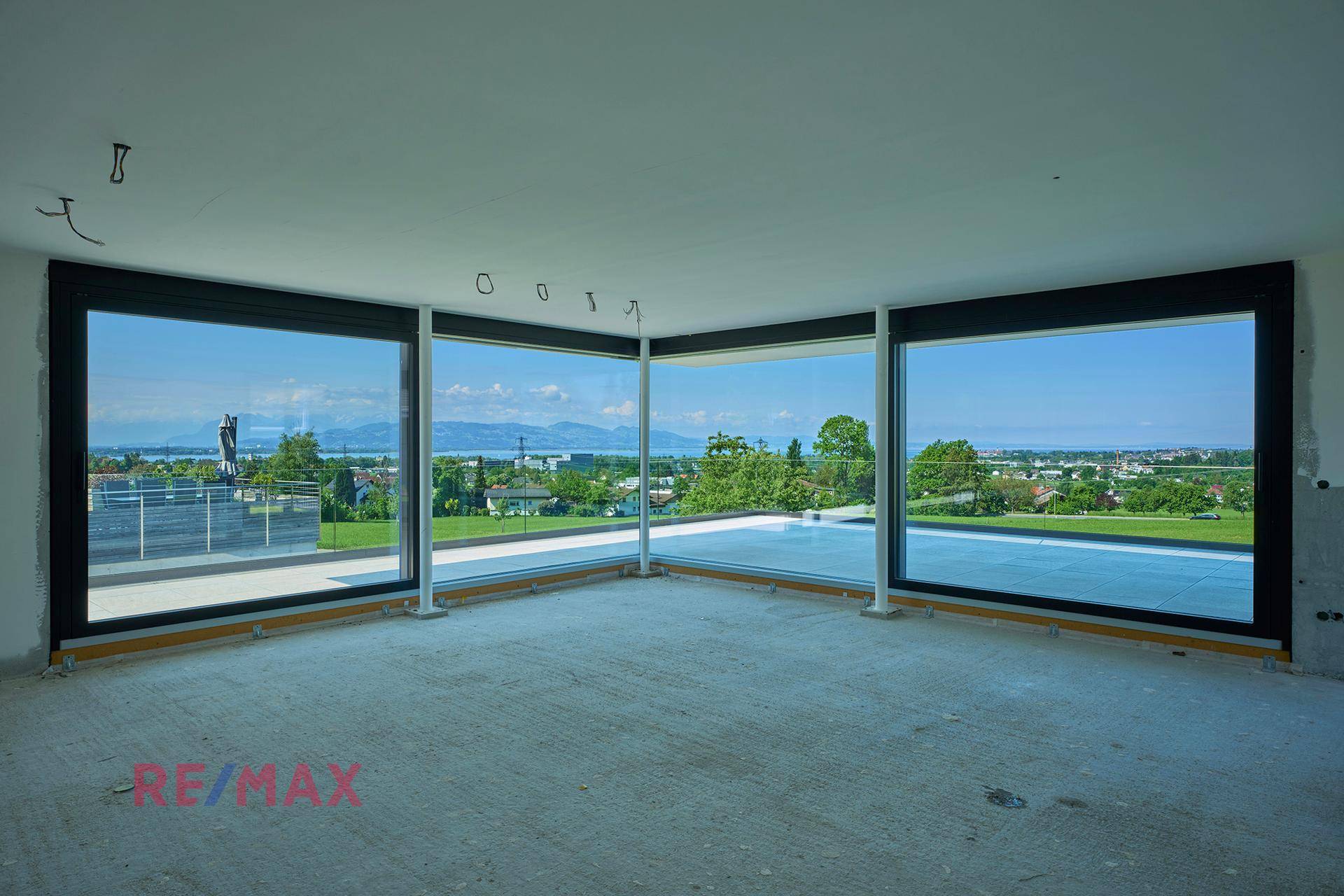Unfertiger Innenraum mit großen Fenstern, die einen weiten Blick auf die Landschaft bieten.