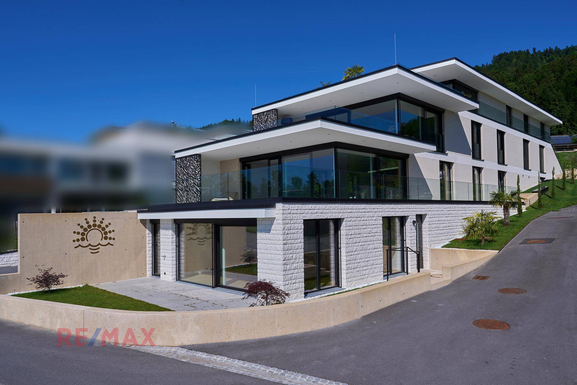 Elegantes Neubaugebäude mit moderner Architektur, Terrassen und großen Fensterfronten.