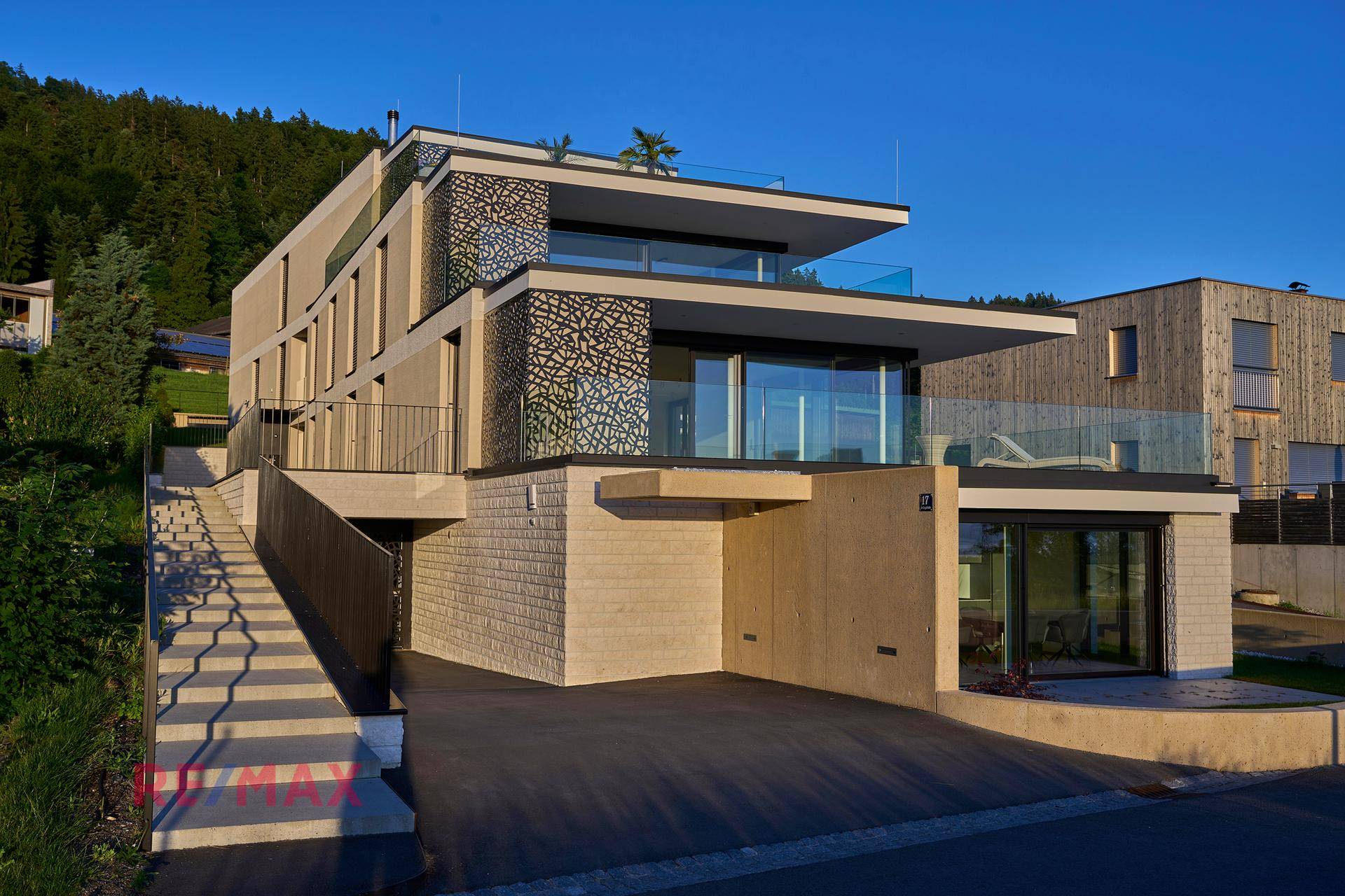 Modernes Wohngebäude mit mehreren Etagen, Terrassen und integrierter Tiefgarage.