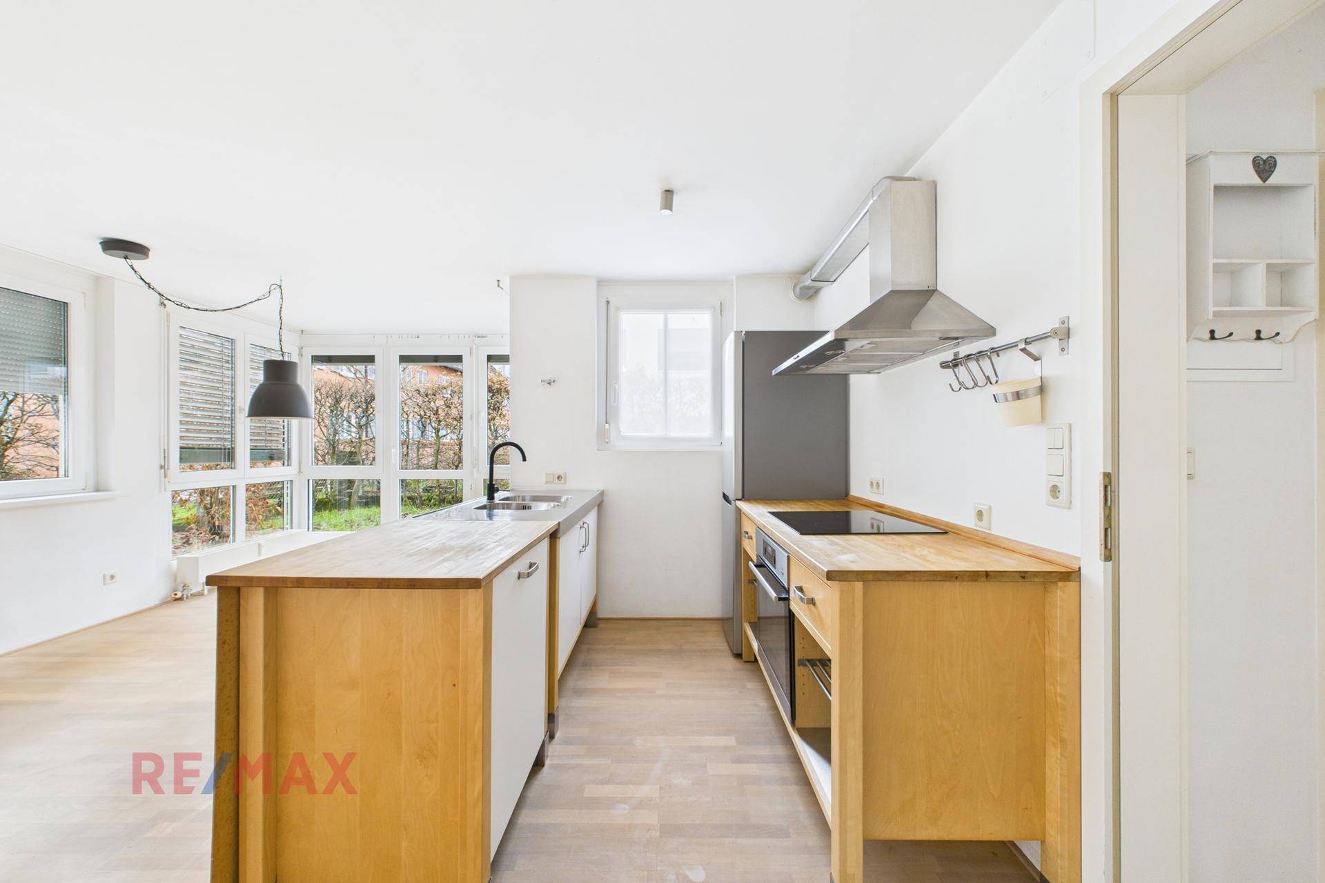 Moderne Küche mit Holzarbeitsplatten, integrierten Geräten und Blick ins Grüne.