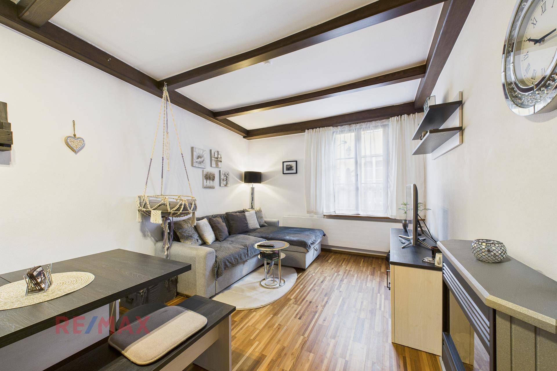 Wohn-Essbereich mit Holzbalkendecke, Parkettboden und gemütlicher Sitzecke mit Esstisch.