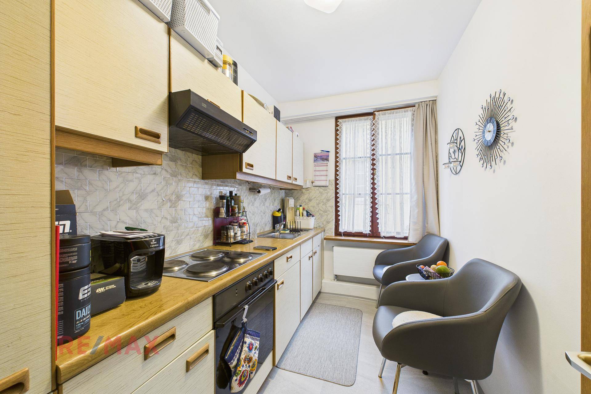 Funktionale Küche mit hellen Holzschränken, Elektroherd und kleinem Essbereich am Fenster.