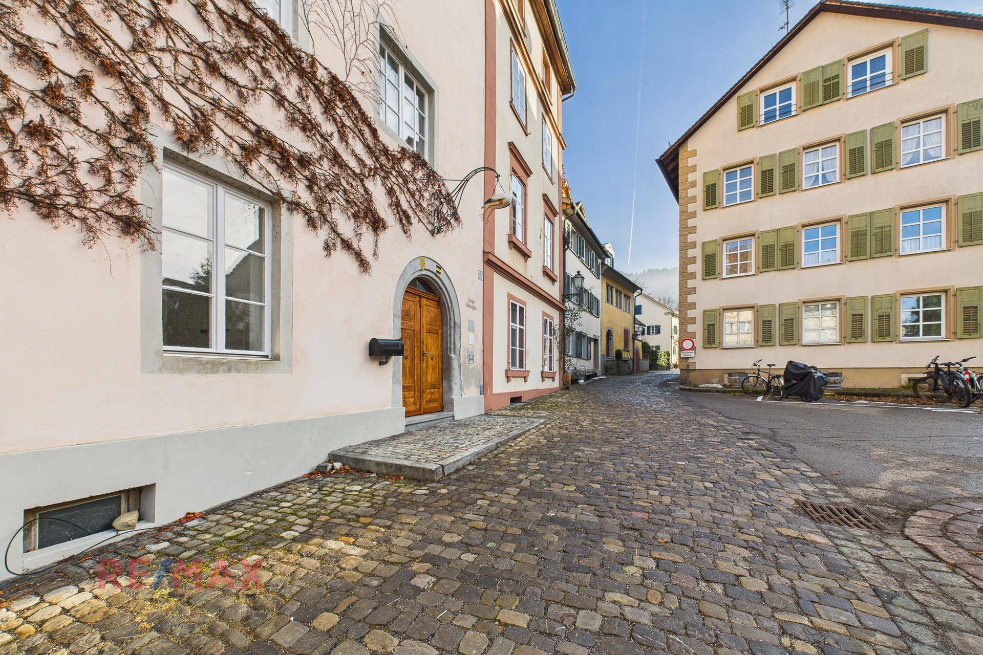 Malerische Gasse mit historischen Gebäuden und Kopfsteinpflaster unter blauem Himmel.