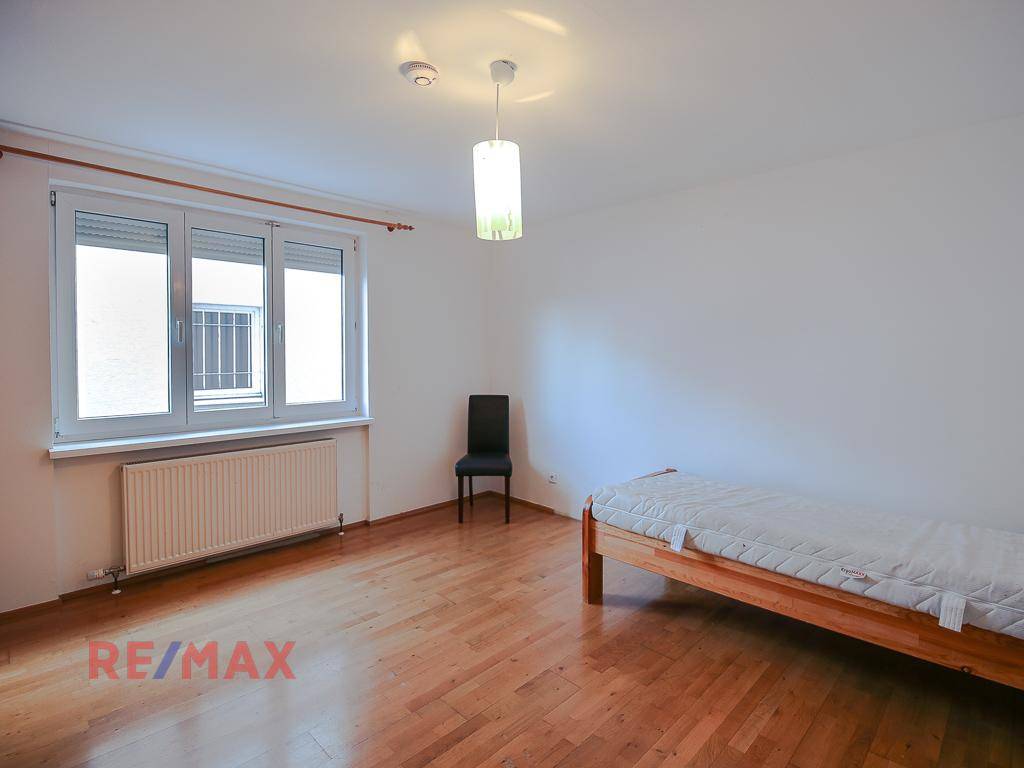 Schlafzimmer mit Holzboden, großem Fenster und einem Einzelbett.