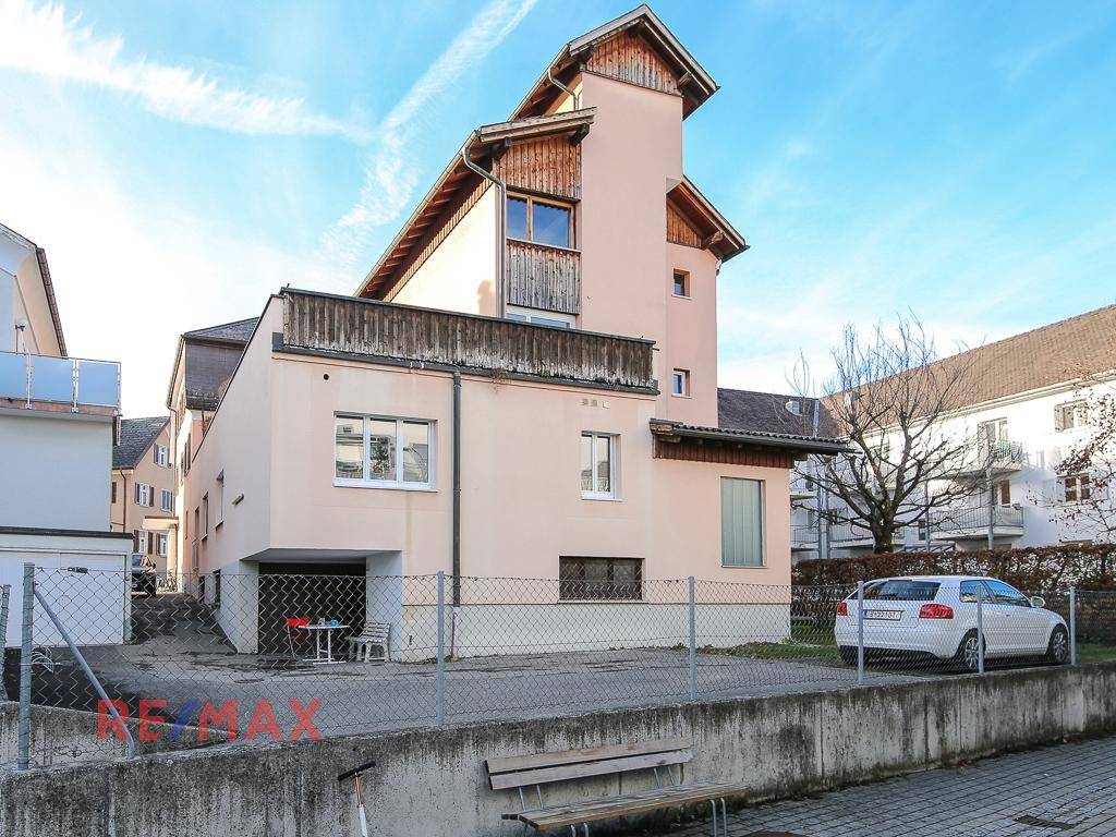 Seitenansicht des Gebäudes mit Garagenzufahrt und angrenzendem Grundstück.