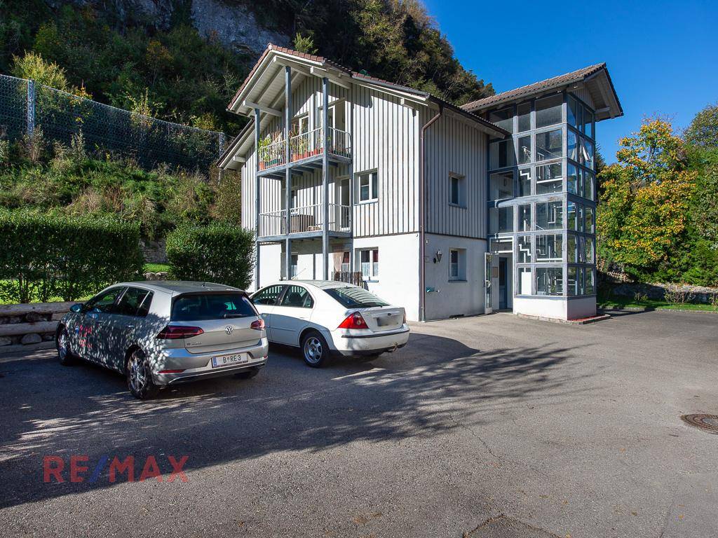 Ansicht des Gebäudes mit Parkplätzen und einem modernen Glasanbau an der Seite.