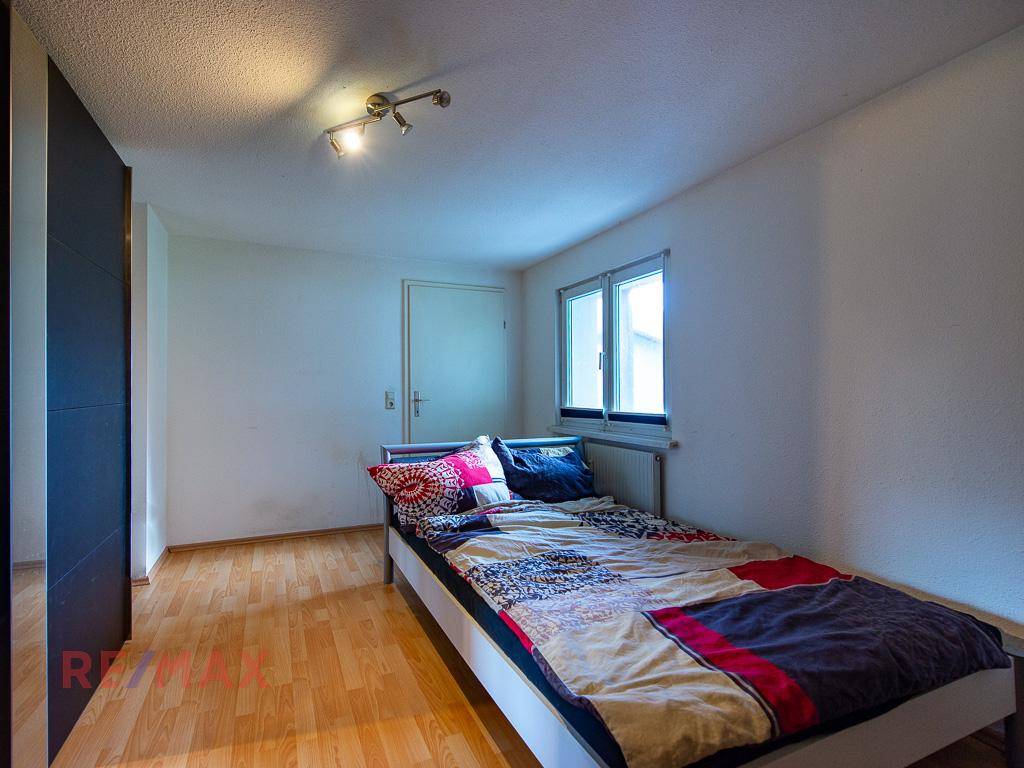 Schlafzimmer mit Einzelbett, Holzboden und Fenster für natürliches Licht.