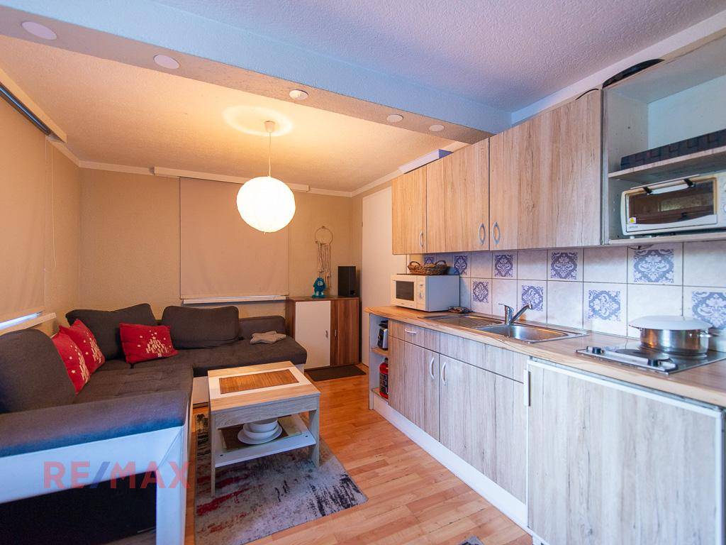 Offener Wohnbereich mit Küchenzeile, Sofa und hellem Holzboden.
