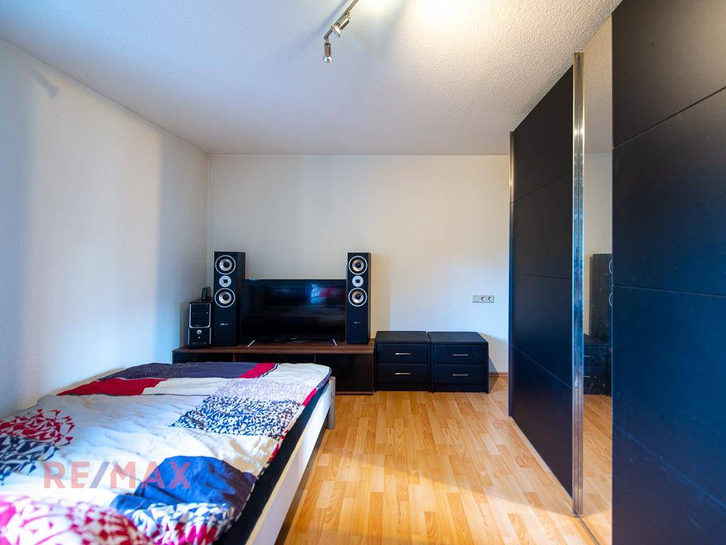 Schlafzimmer mit Holzboden, Einzelbett und Unterhaltungselektronik.