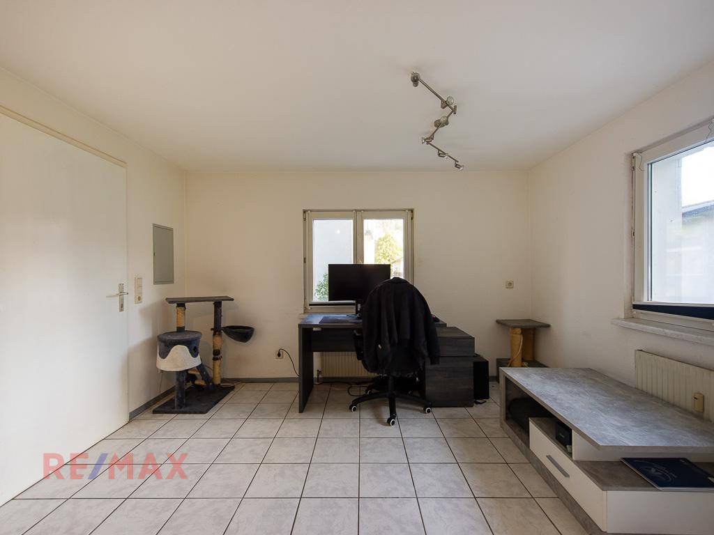 Helles Arbeitszimmer mit Fliesenboden und Fenster für natürliches Licht.