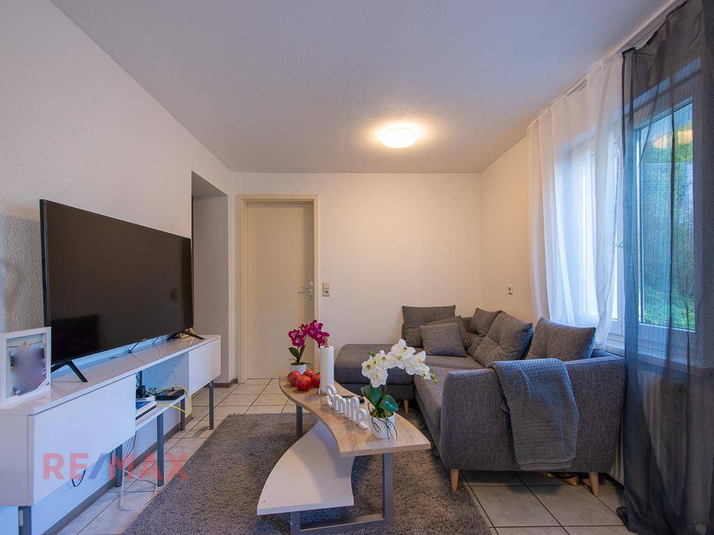 Gemütliches Wohnzimmer mit Sofa, Couchtisch und Fliesenboden.