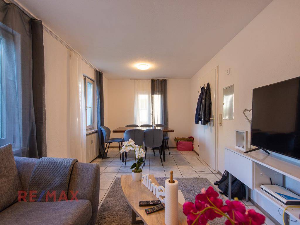 Geräumiger Wohn- und Essbereich mit Sofa, Esstisch und Fliesenboden.