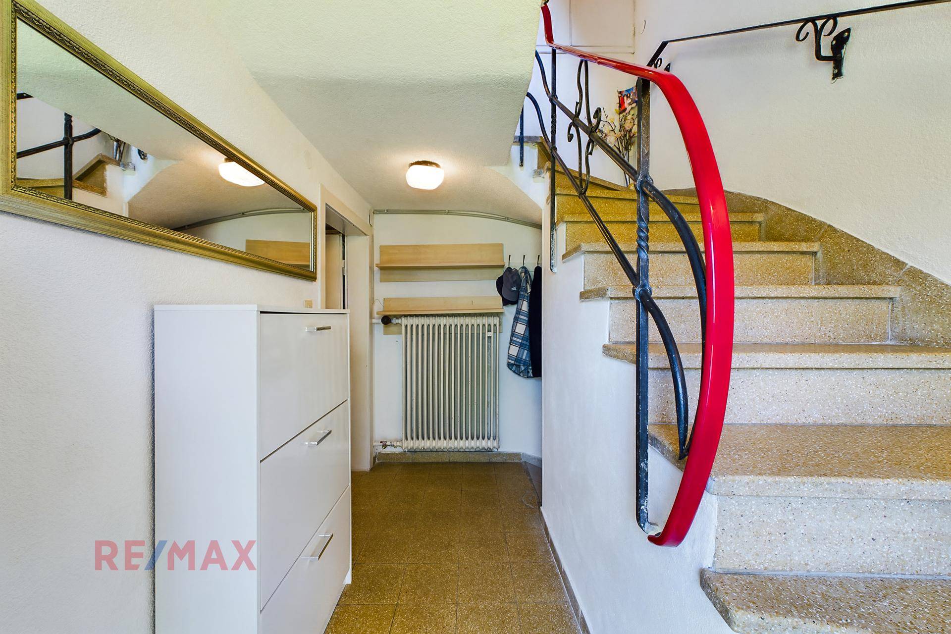 Heller Eingangsbereich mit Steintreppe, schmiedeeisernem Geländer und einem großen Spiegel an der Wand.