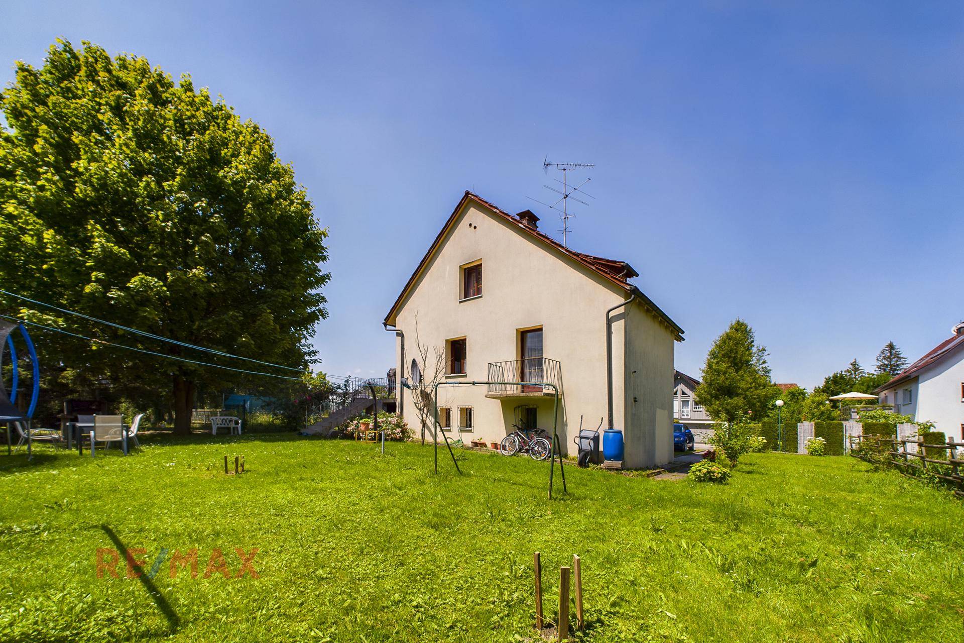 Rückansicht des Einfamilienhauses mit großem Garten, gepflegter Rasenfläche und altem Baumbestand.