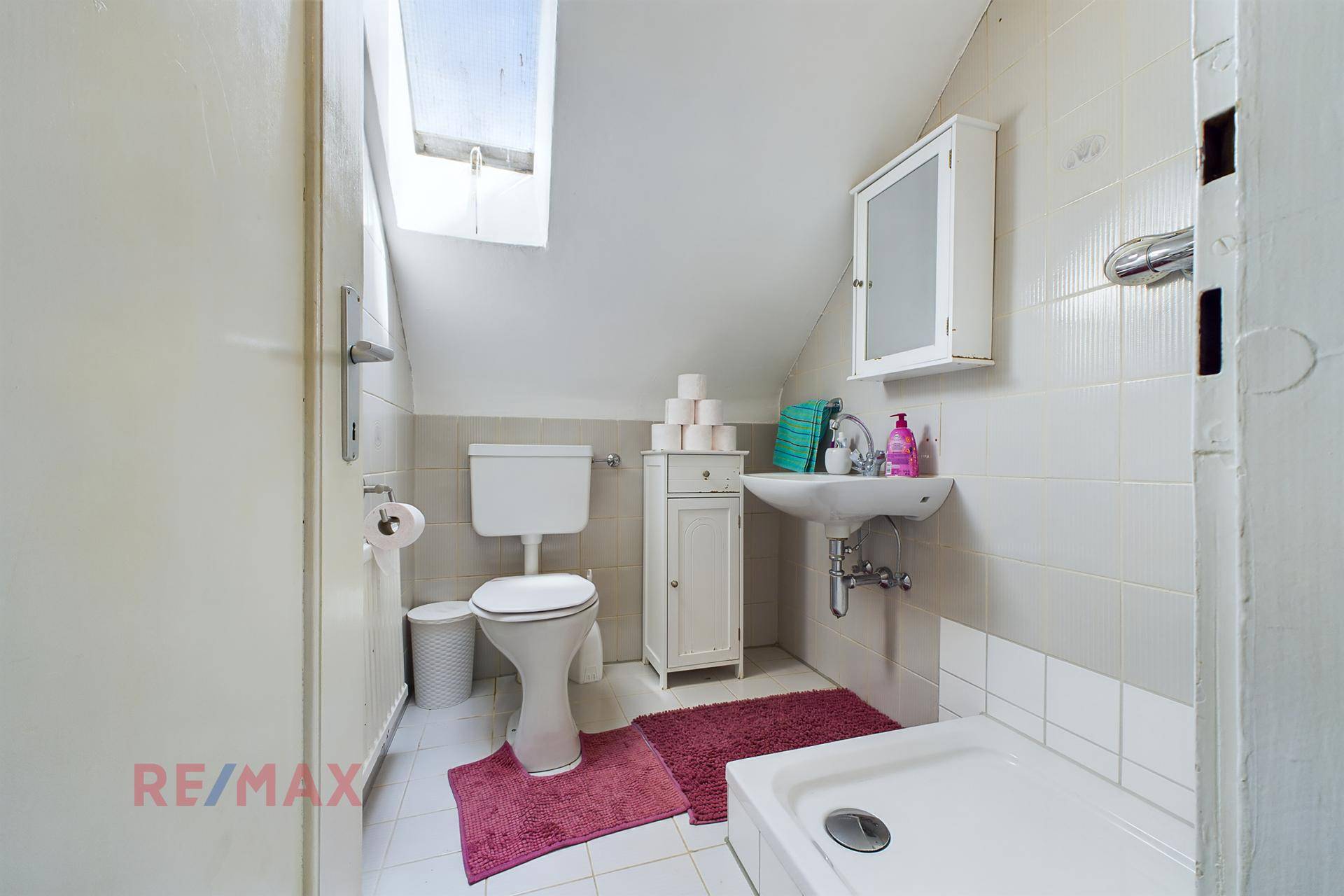 Badezimmer im Dachgeschoss mit WC, Waschbecken, Dusche und einem praktischen Dachfenster.