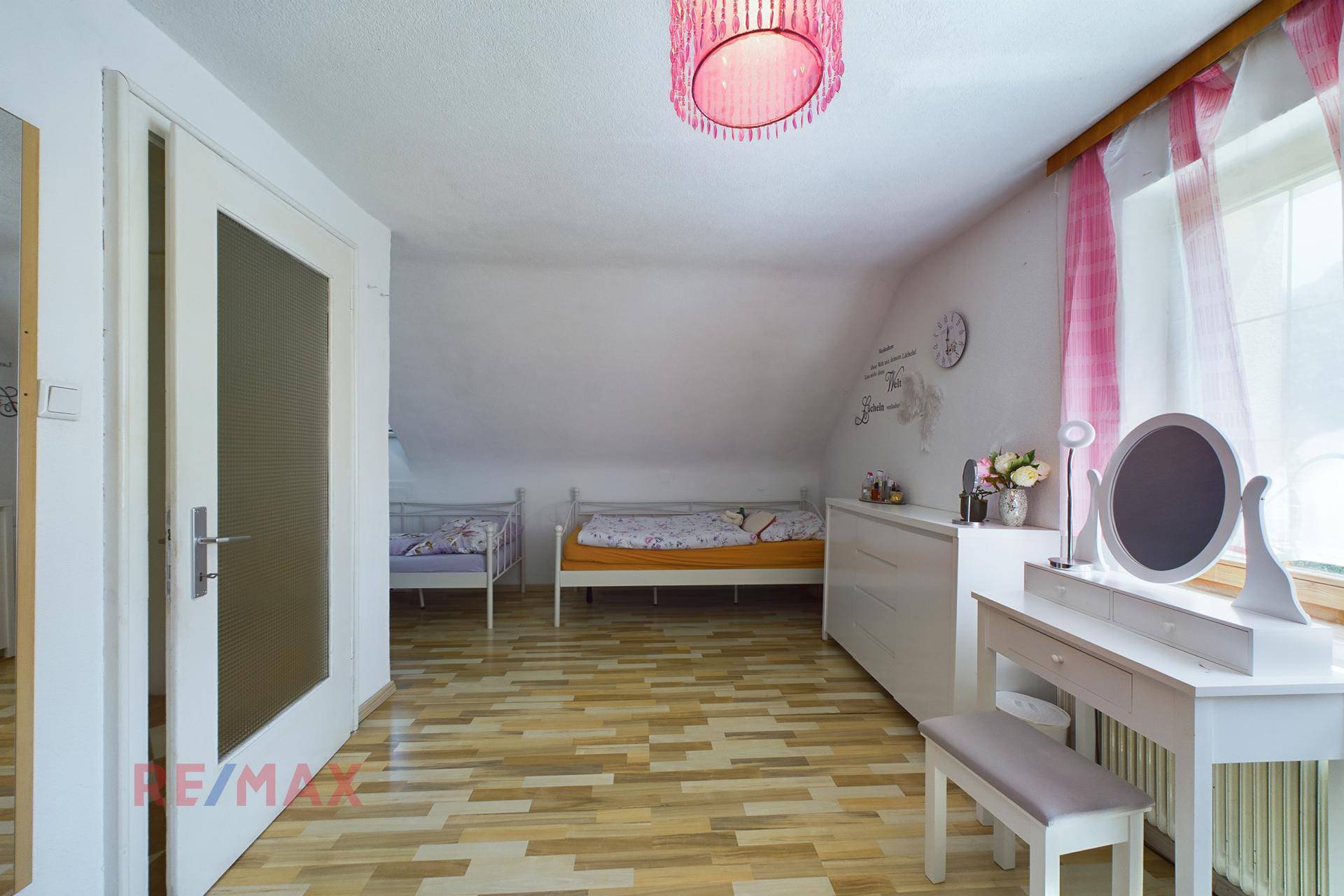 Kinderzimmer im Dachgeschoss mit zwei Betten, Schminktisch und hellem Holzfußboden.