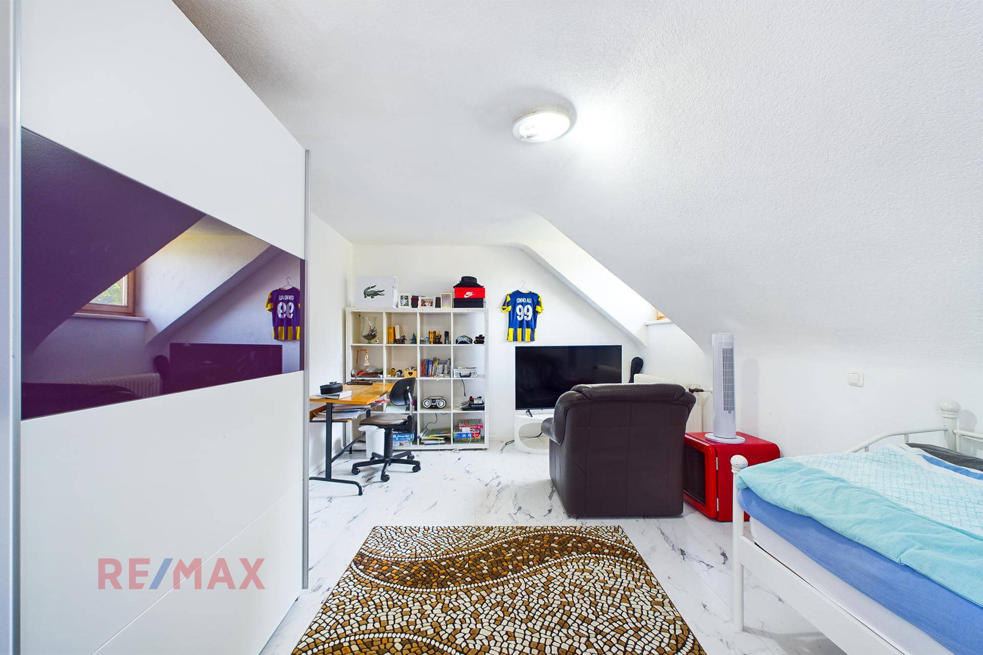 Geräumiges Schlafzimmer im Dachgeschoss mit Schrägen, Bett und viel Stauraum.