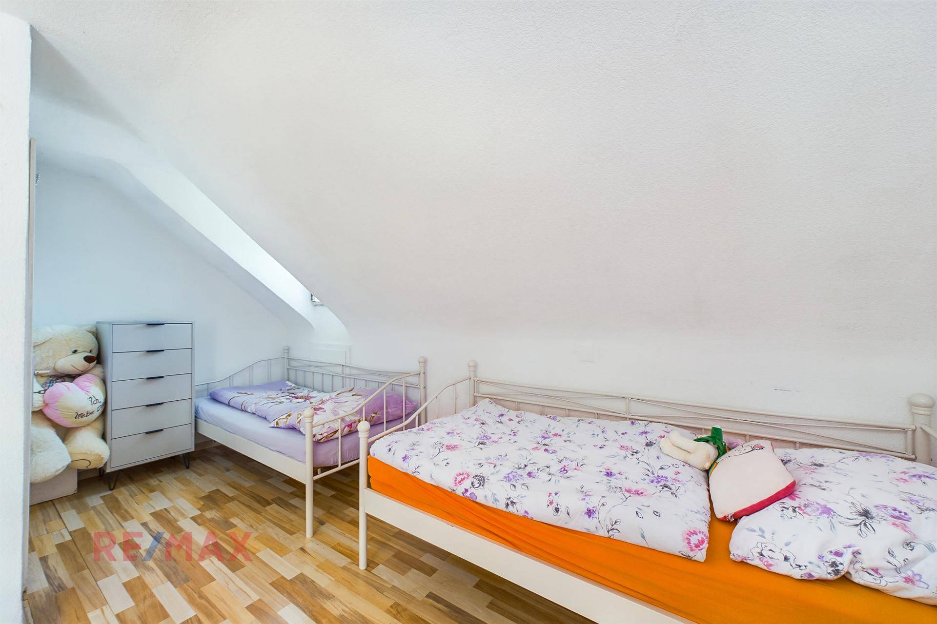 Kinderzimmer im Dachgeschoss mit zwei Betten, Dachschräge und hellem Holzboden.