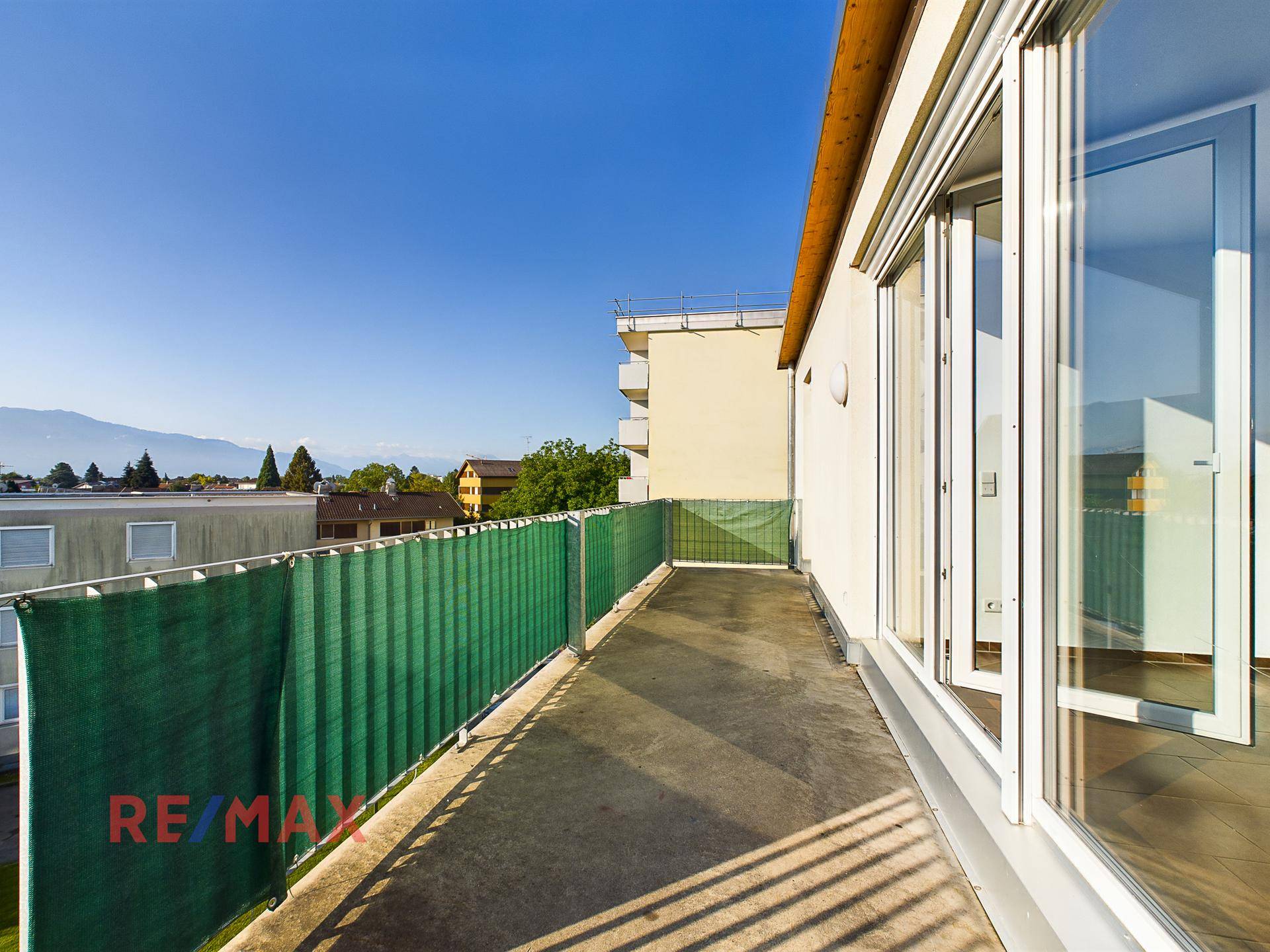 Geräumiger Balkon mit grüner Sichtschutzwand und Blick auf die Umgebung.