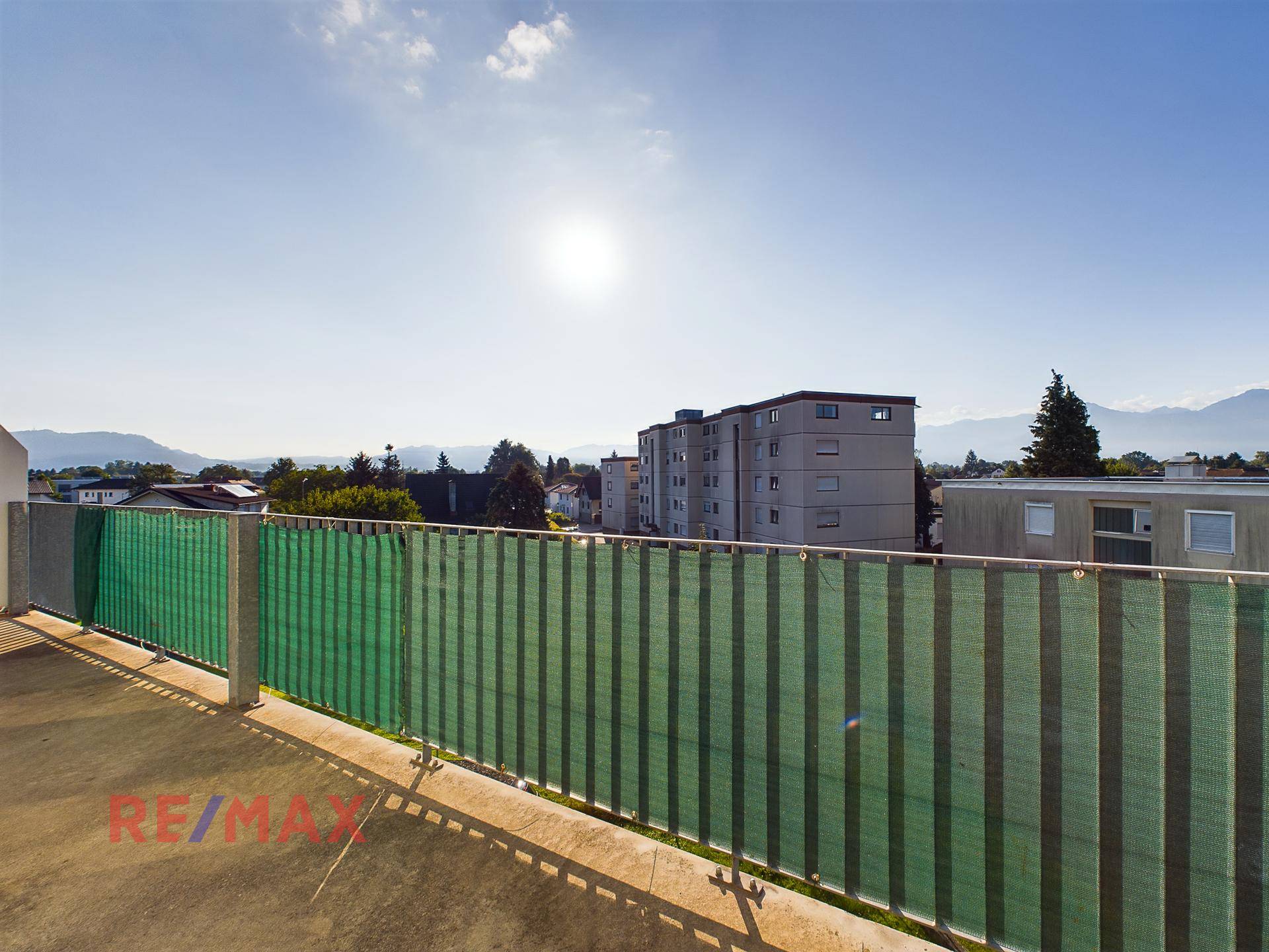 Sonniger Balkon mit weitem Blick über die Stadt und die umliegenden Berge.