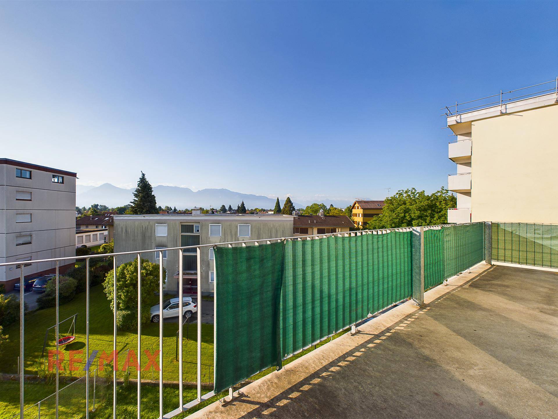 Balkon mit Blick auf den grünen Innenhof und die umliegenden Gebäude.