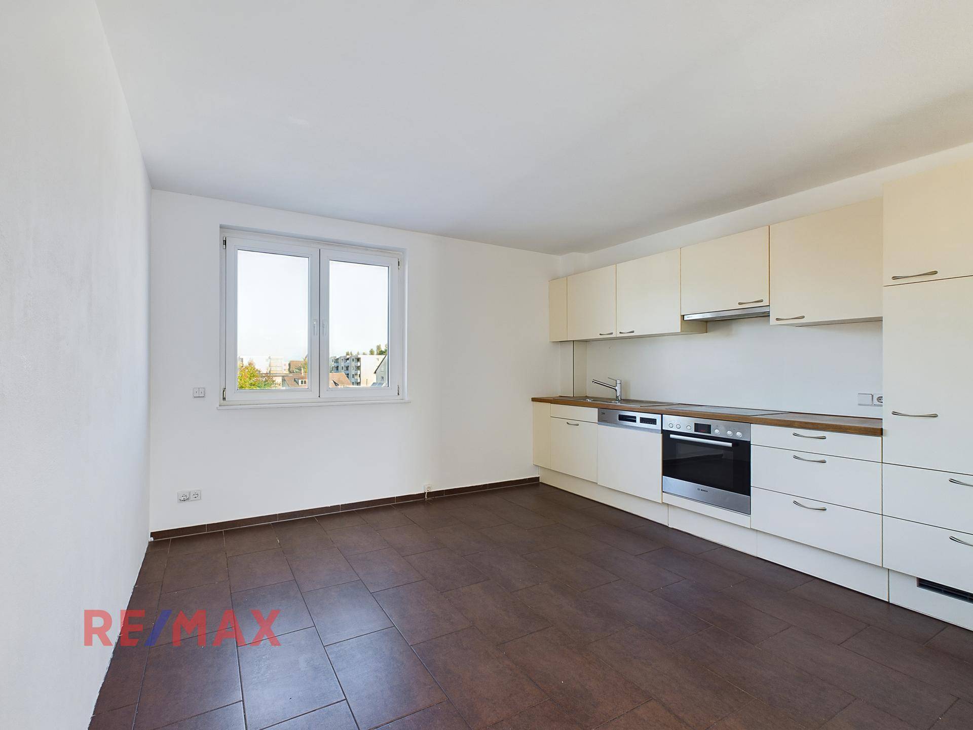 Funktionale Küche mit hellen Einbauschränken, Holztheke und Fenster.